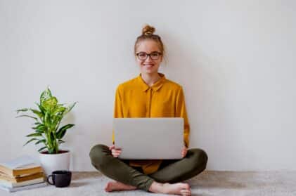 Nainen istuu lattialla tietokoneen kanssa